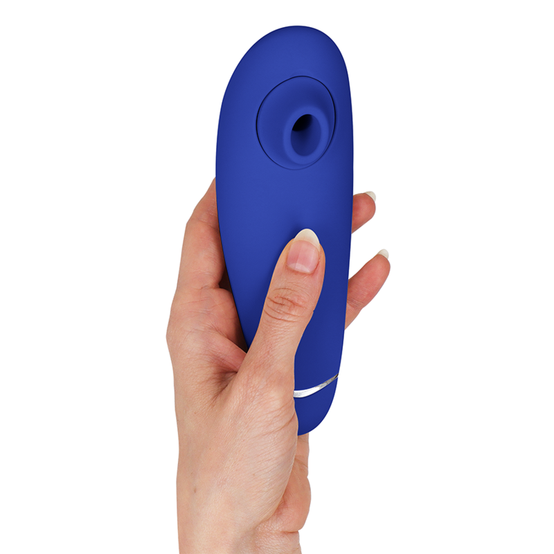 Blueberry-colored ergonomic clitoral stimulator with circular suction head held in hand.