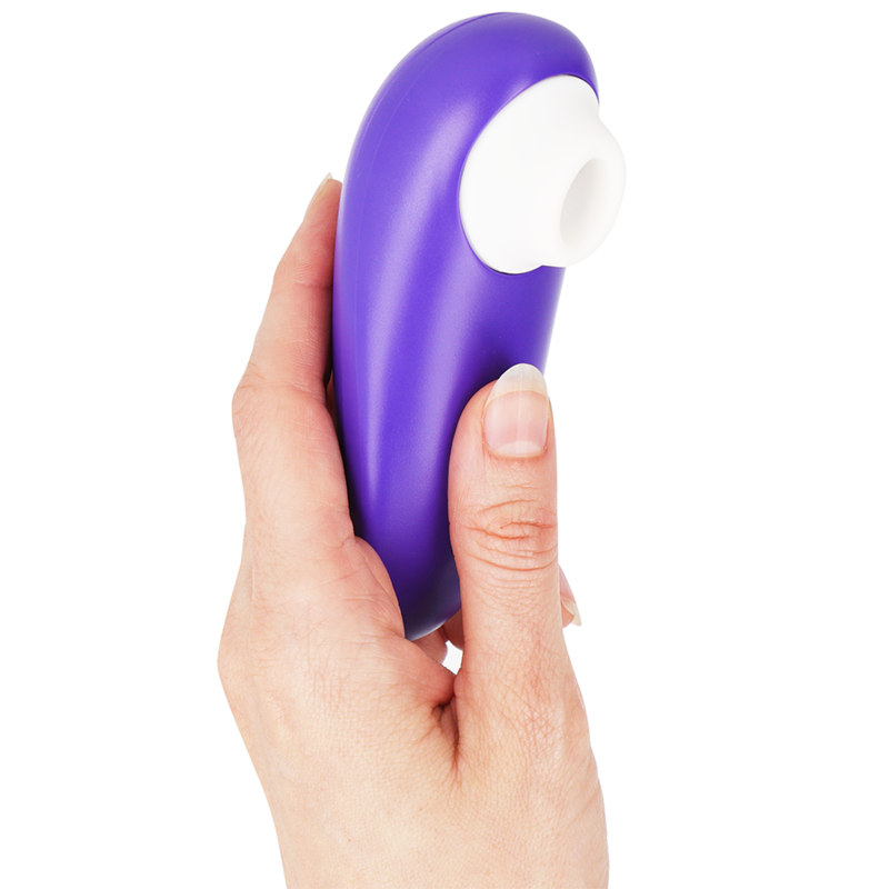 Compact indigo clitoral stimulator with white silicone tip held in hand.