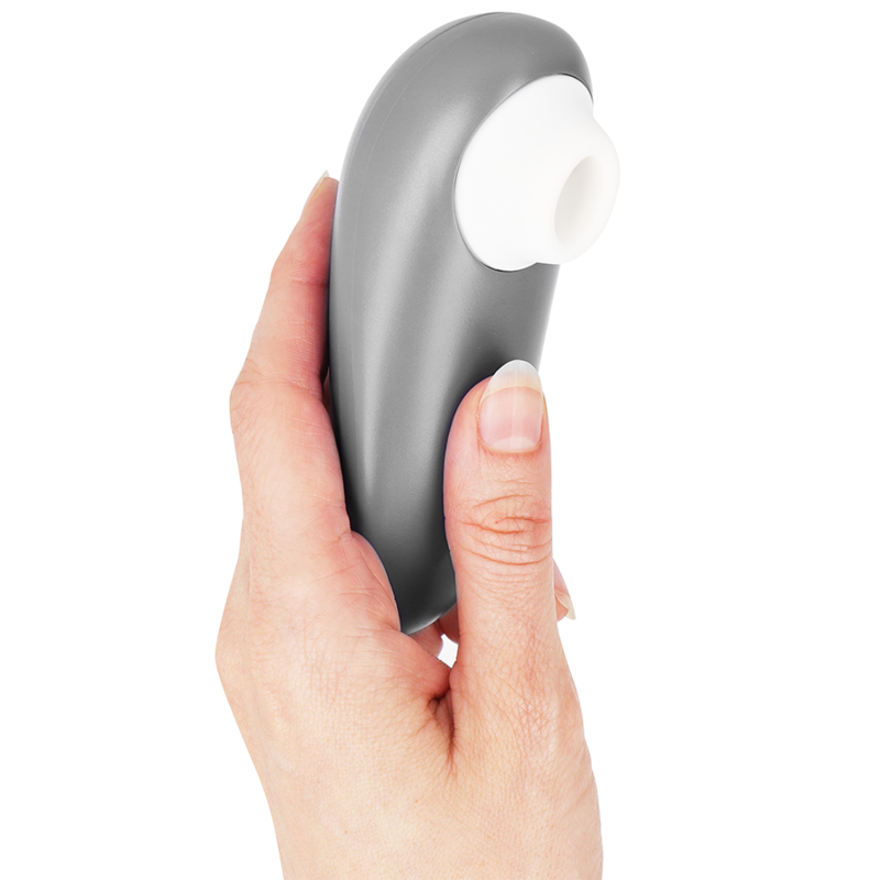 Compact gray clitoral stimulator with white silicone suction head held in hand.