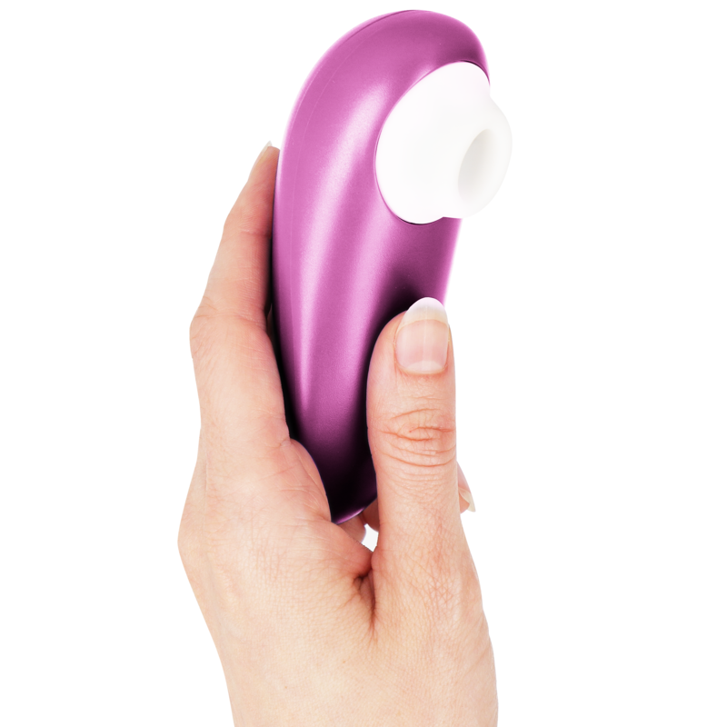 Compact violet clitoral stimulator with white silicone nozzle held in hand.