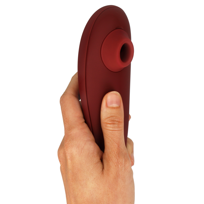 Bordeaux clitoral stimulator with ergonomic curved design held in hand.