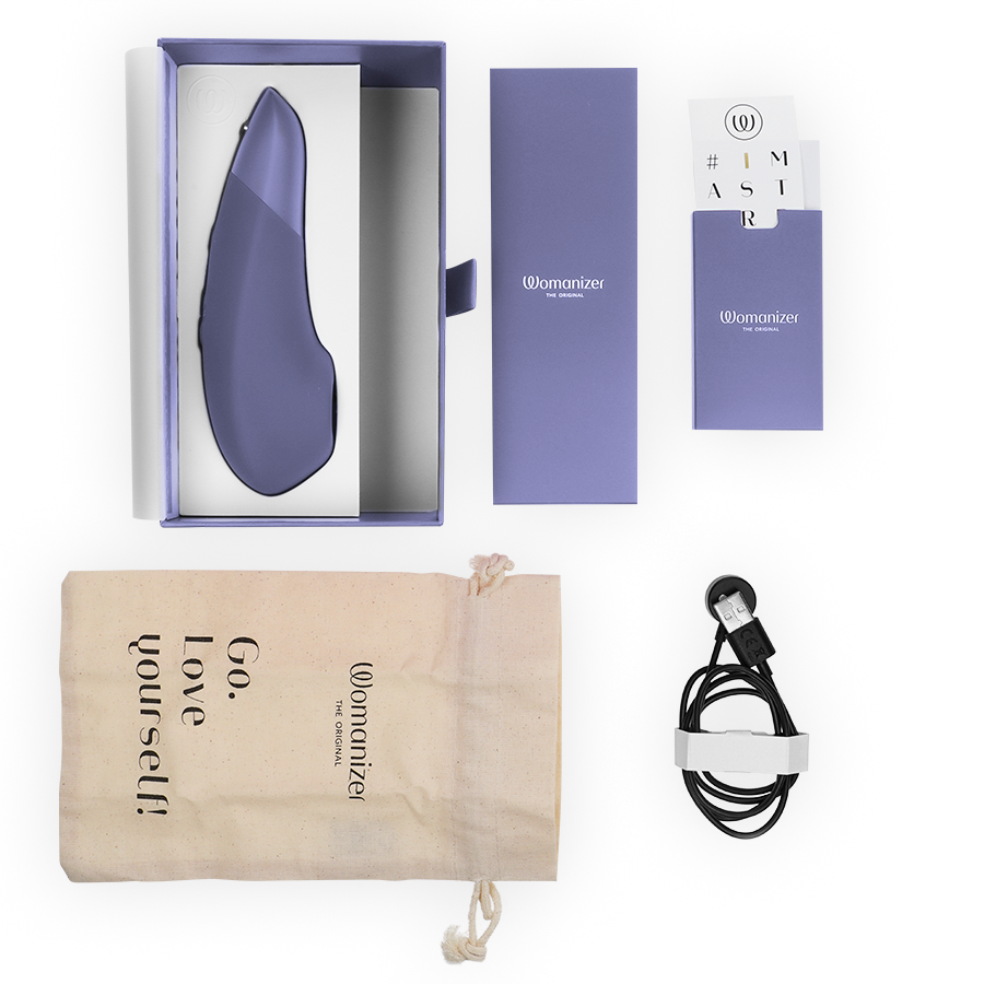 Lilac Womanizer Enhance clitoral stimulator with box, drawstring pouch, instruction manual, and charging cable.