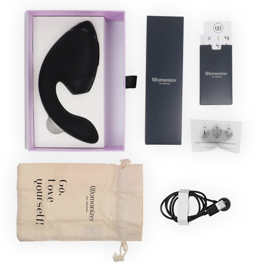 Black dual clitoral and G-spot stimulator with curved silicone design, USB charging cable, instruction manuals, and beige.