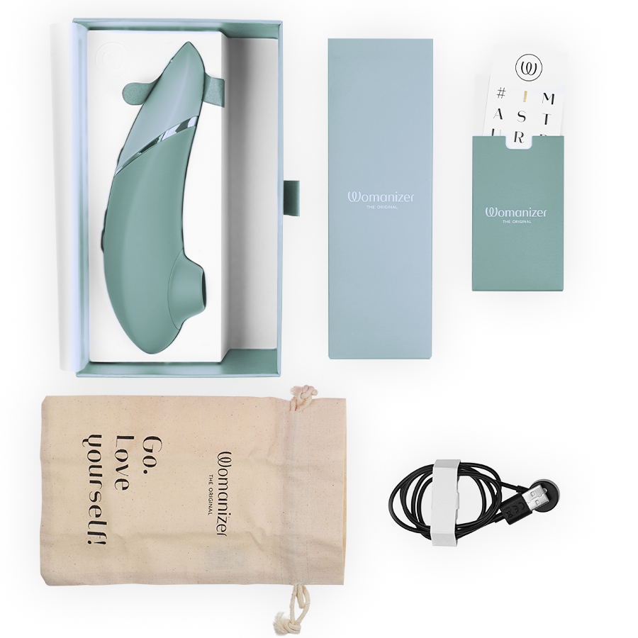 Sage green Womanizer Next clitoral stimulator with packaging, drawstring storage pouch, USB charging cable, and instruction.