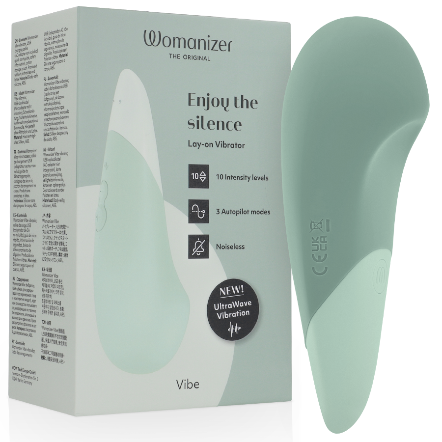 Sage green Womanizer Vibe Lay-On silent vibrator with smooth curved design next to matching product box.
