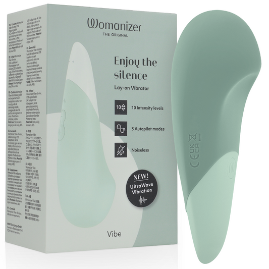 Sage green Womanizer Vibe Lay-On silent vibrator with smooth curved design next to matching product box.