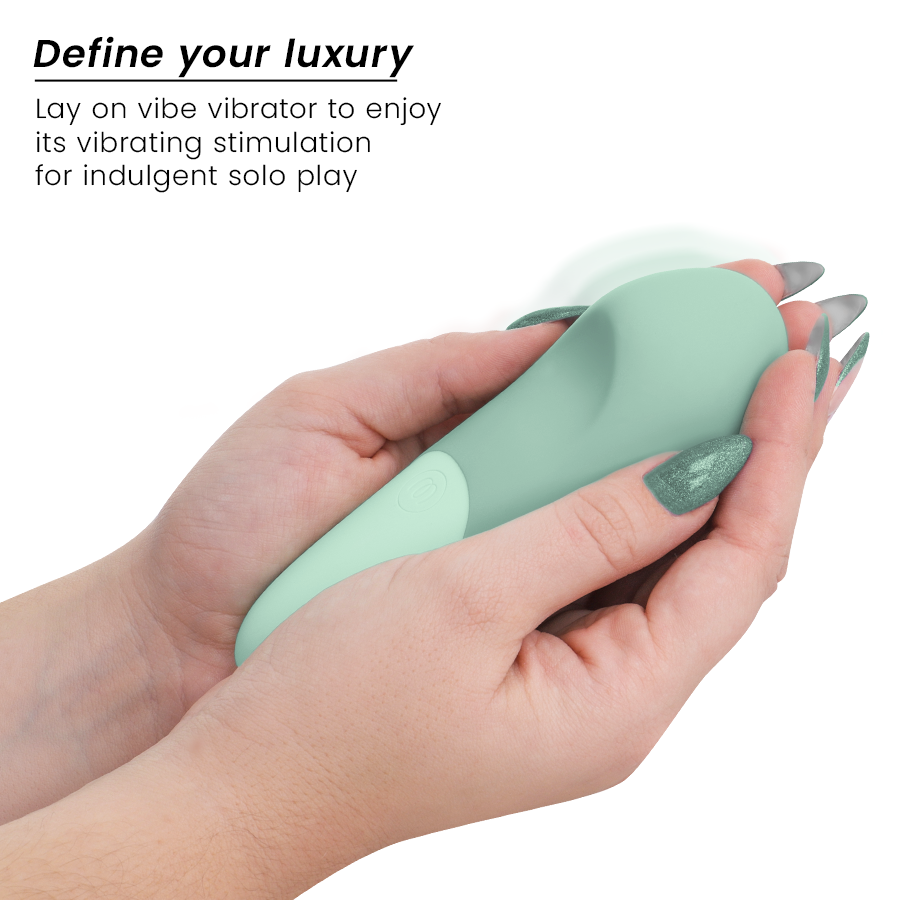 Sage green Womanizer Vibe lay-on vibrator held in hands with long manicured nails.