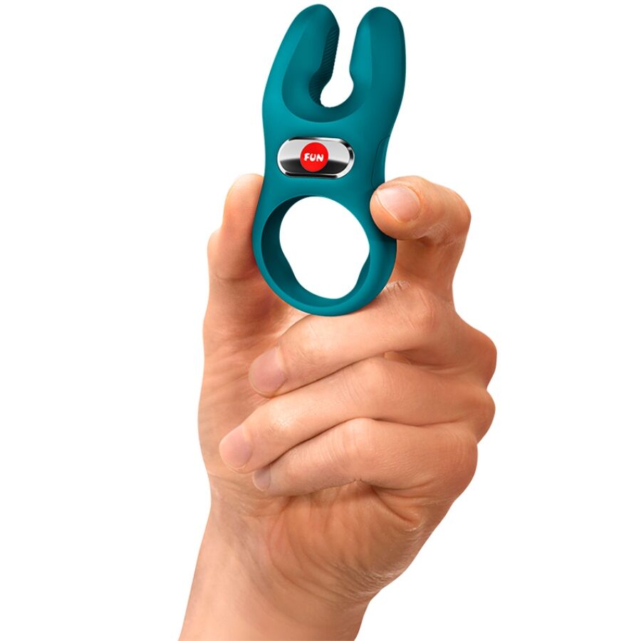 Bottle green silicone vibrating cock ring with dual prongs held by hand.