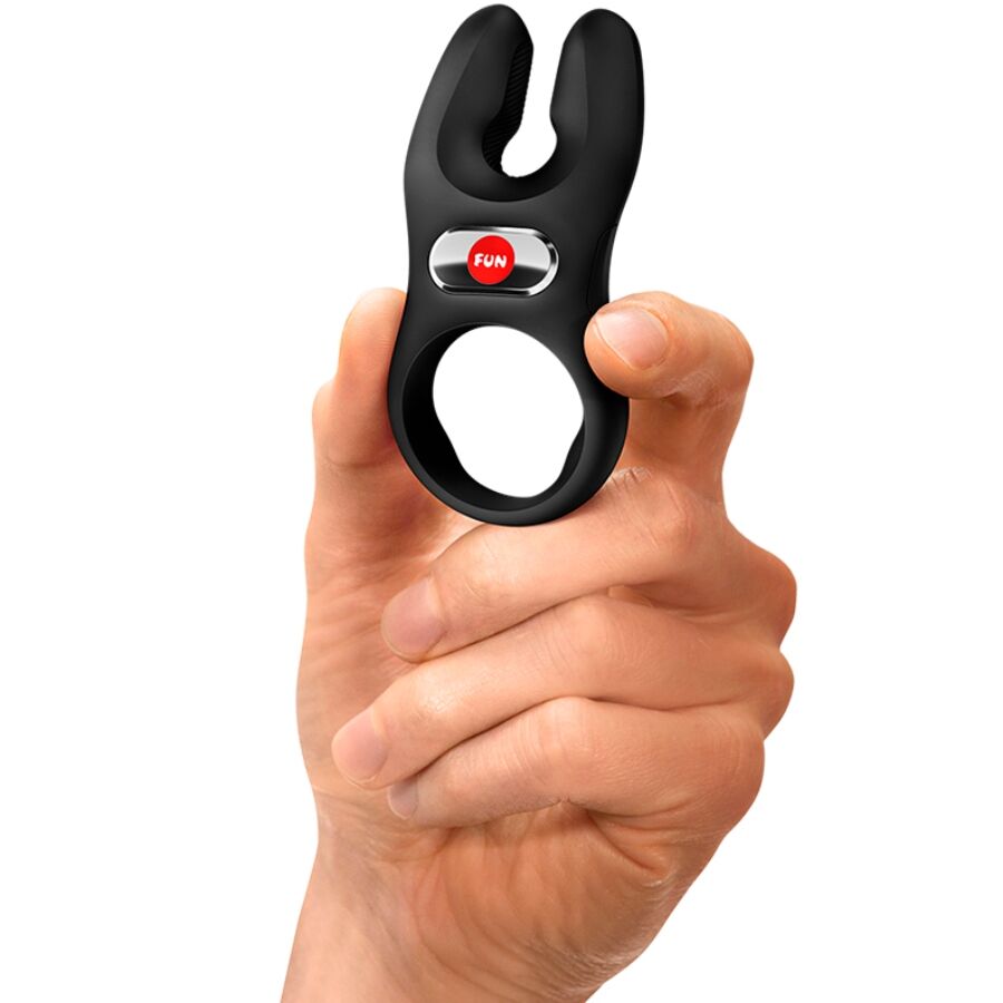 Black silicone vibrating cock ring with dual prongs held between fingers.