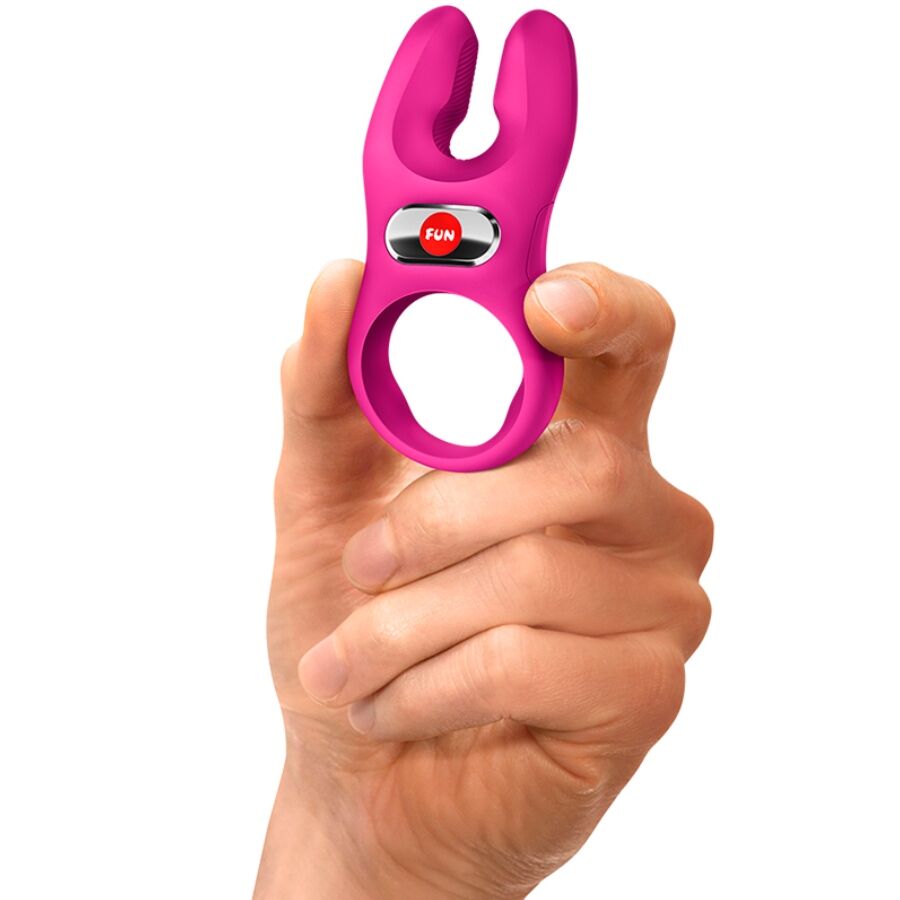 Magenta silicone vibrating cock ring with dual prongs held between fingers.